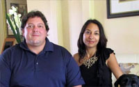 Article photo: a man and a woman sitting side by side in a living room, looking at the camera